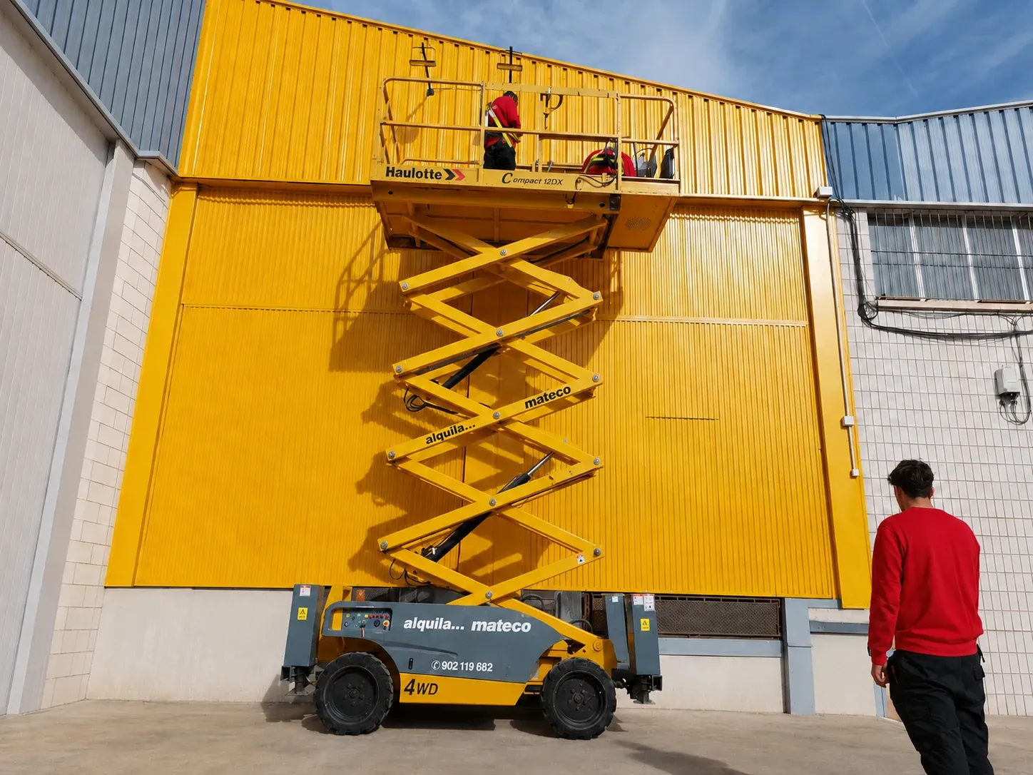 Instalación de un rótulo de gran formato en la fachada de una nave industrial mediante una plataforma elevadora tipo tijera