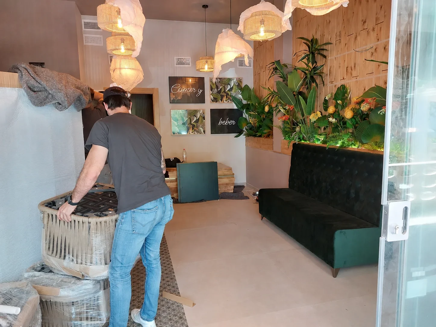 Montaje del mobiliario en el salón del restaurante Los Dos en El Campello durante la obra, con la pared de madera, la vegetación y el banco corrido ya instalados