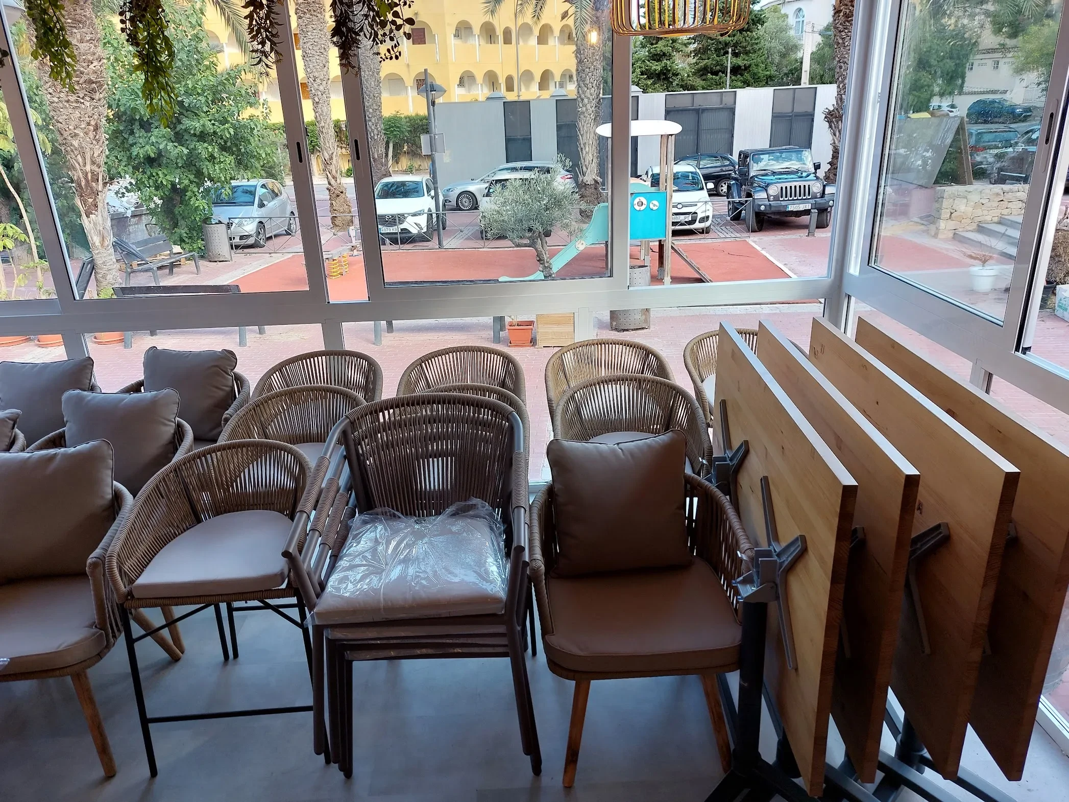 Mesas de la terraza del restaurante Los Dos en El Campello con el tablero girado en vertical para guardarlas en un mínimo espacio, apiladas junto a las sillas tapizadas