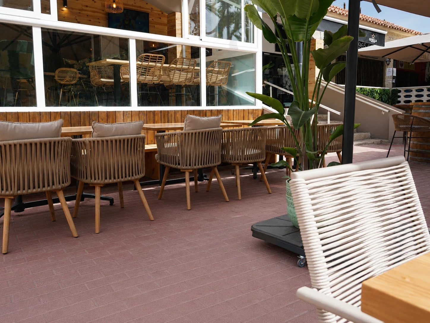 Terraza exterior del restaurante Los Dos en El Campello con banco corrido tapizado y mesas de madera