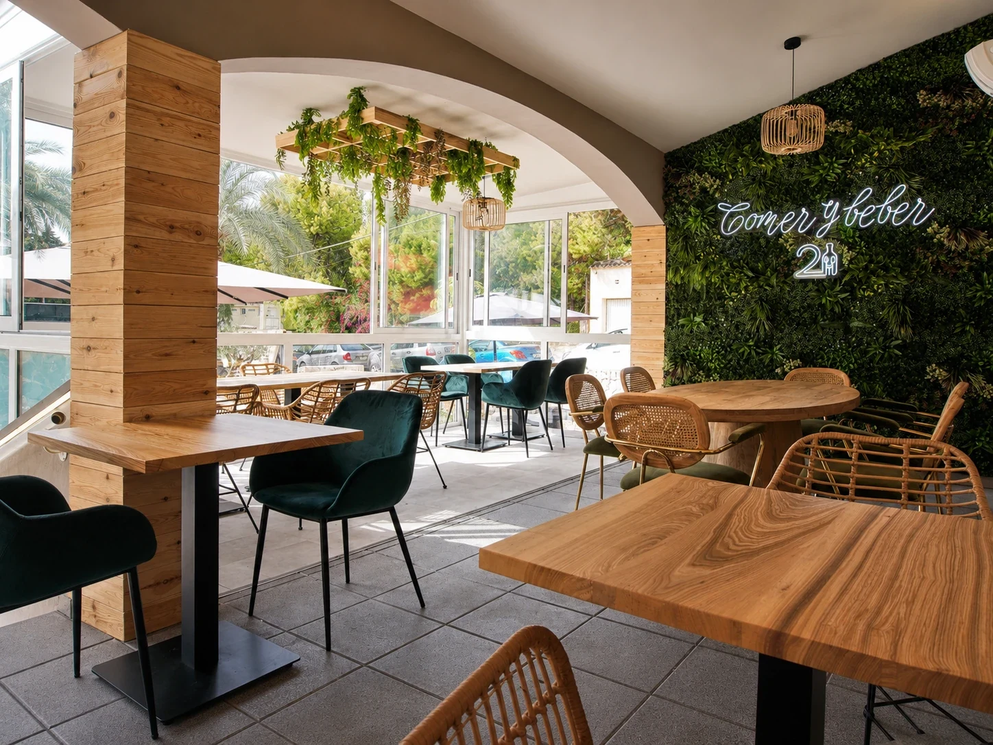 Terraza del restaurante Los Dos en El Campello con mesas redondas, sillas, vegetación e iluminación cálida